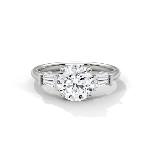 Front view of a solid white gold three-stone engagement ring showcasing a brilliant round center diamond and two tapered baguette side stones.