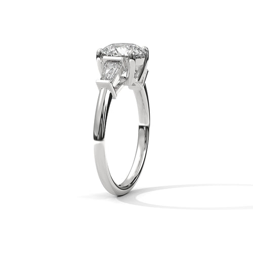 Three-quarter angled view of the polished white gold three-stone ring highlighting the clean lines of the tapered baguette accent stones.