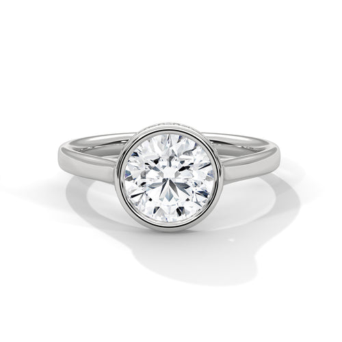 Round brilliant lab-grown diamond engagement ring inside a smooth protective bezel setting on a tapered white gold cathedral band.