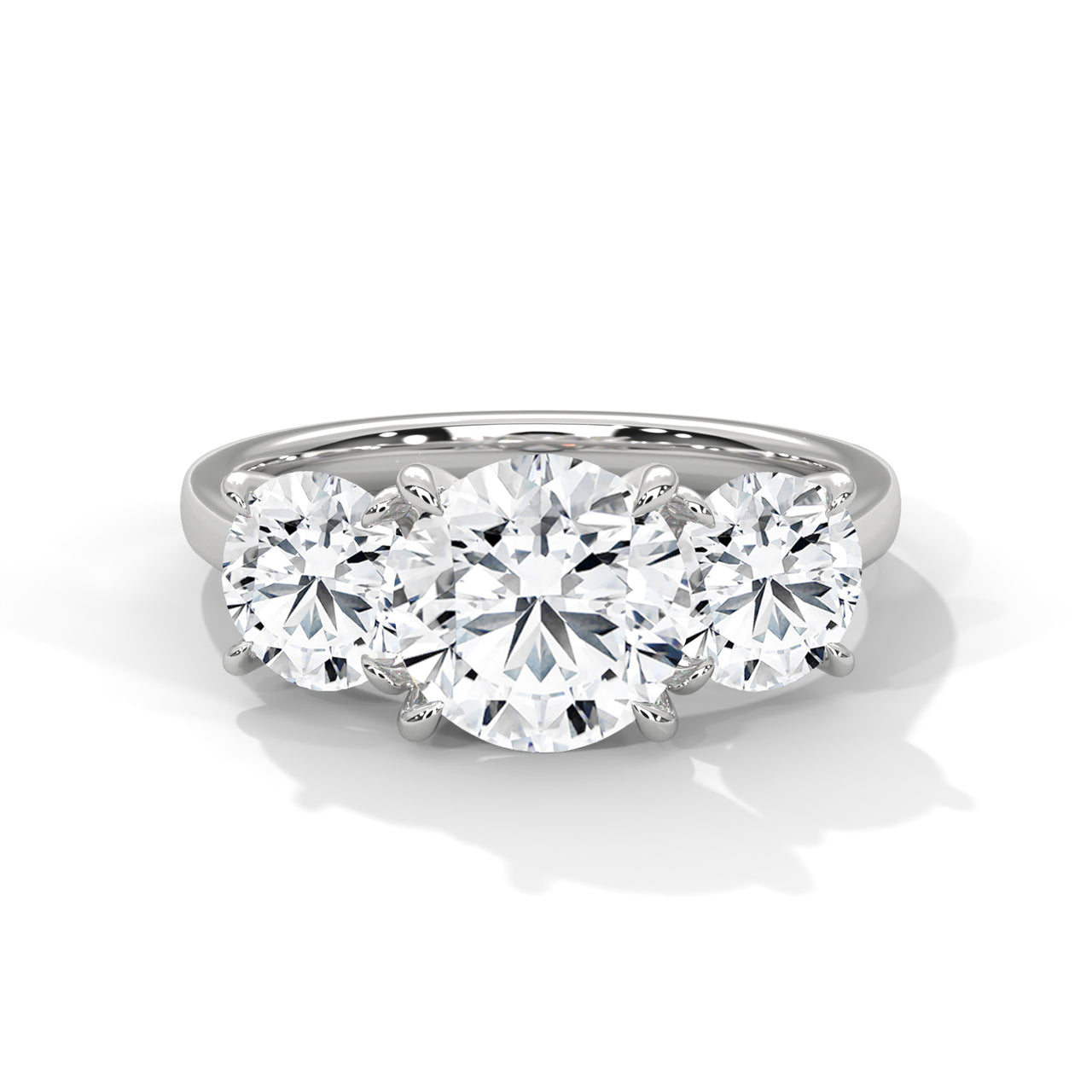 Round brilliant three-stone trilogy engagement ring in white gold, side profile view showing three diamond setting