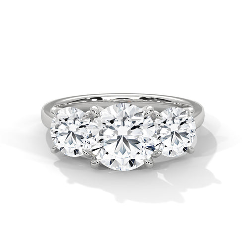 Round brilliant three-stone trilogy engagement ring in white gold, side profile view showing three diamond setting