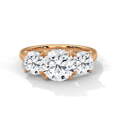 Round brilliant three-stone trilogy engagement ring in rose gold, three-quarter view showing all three stones