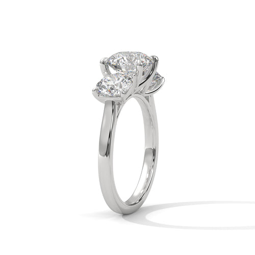 Round brilliant three-stone trilogy engagement ring in white gold, angled view showing center and side stones