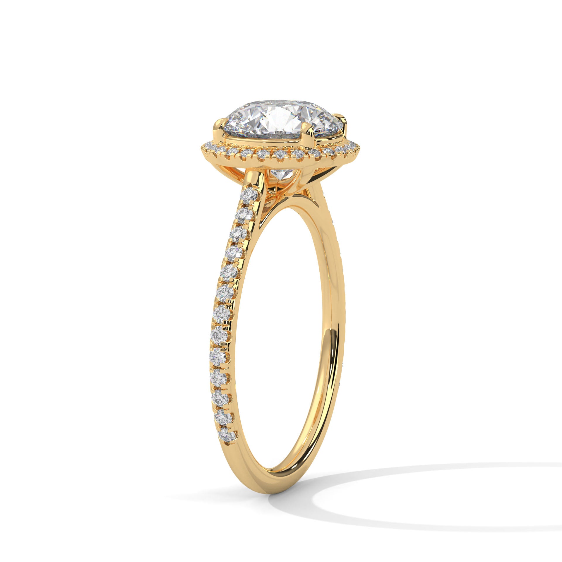 Angled perspective of a round diamond halo engagement ring in yellow gold showcasing the pavé band.