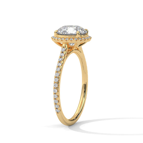 Angled perspective of a round diamond halo engagement ring in yellow gold showcasing the pavé band.
