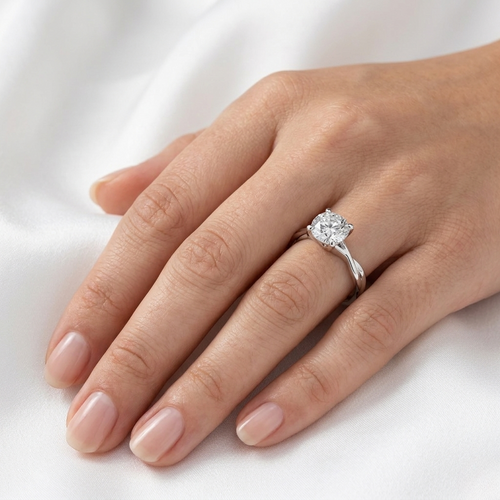 Close-up of a twisted shank diamond solitaire engagement ring in white gold worn on a finger.