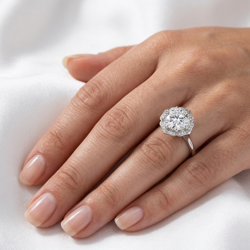 Close-up of a scalloped floral halo diamond engagement ring in white gold worn on a finger.