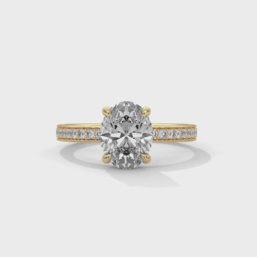 Oval hidden halo micropavé engagement ring in yellow gold, close-up angled view of setting and band