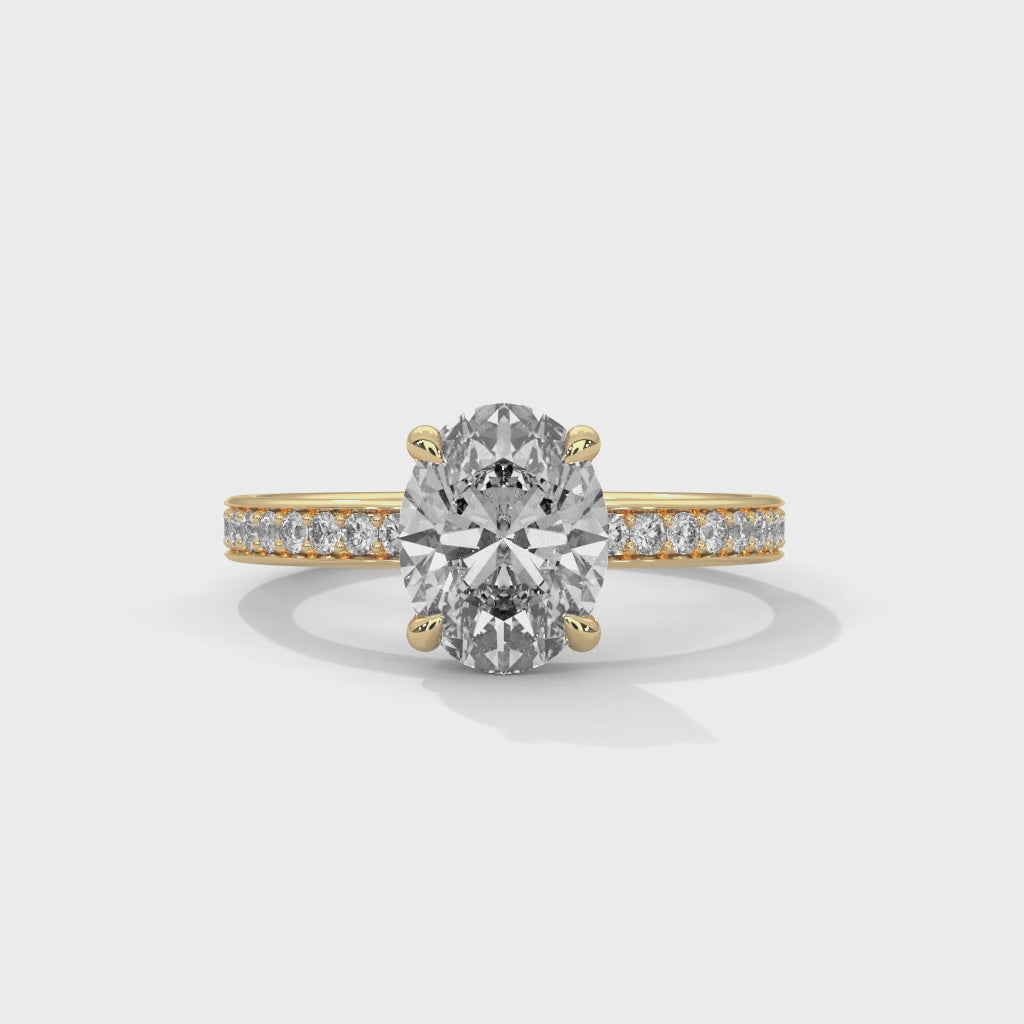 Oval hidden halo micropavé engagement ring in yellow gold, close-up angled view of setting and band