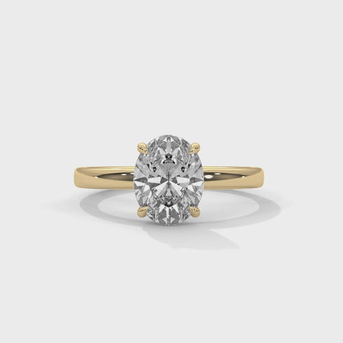Oval solitaire plain band engagement ring in yellow gold, close-up angled view of solitaire setting