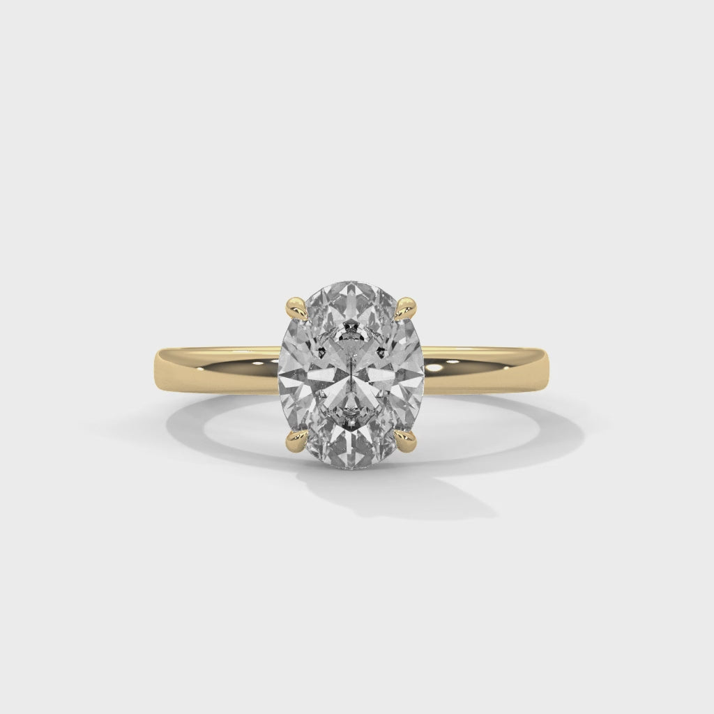 Oval solitaire plain band engagement ring in yellow gold, close-up angled view of solitaire setting